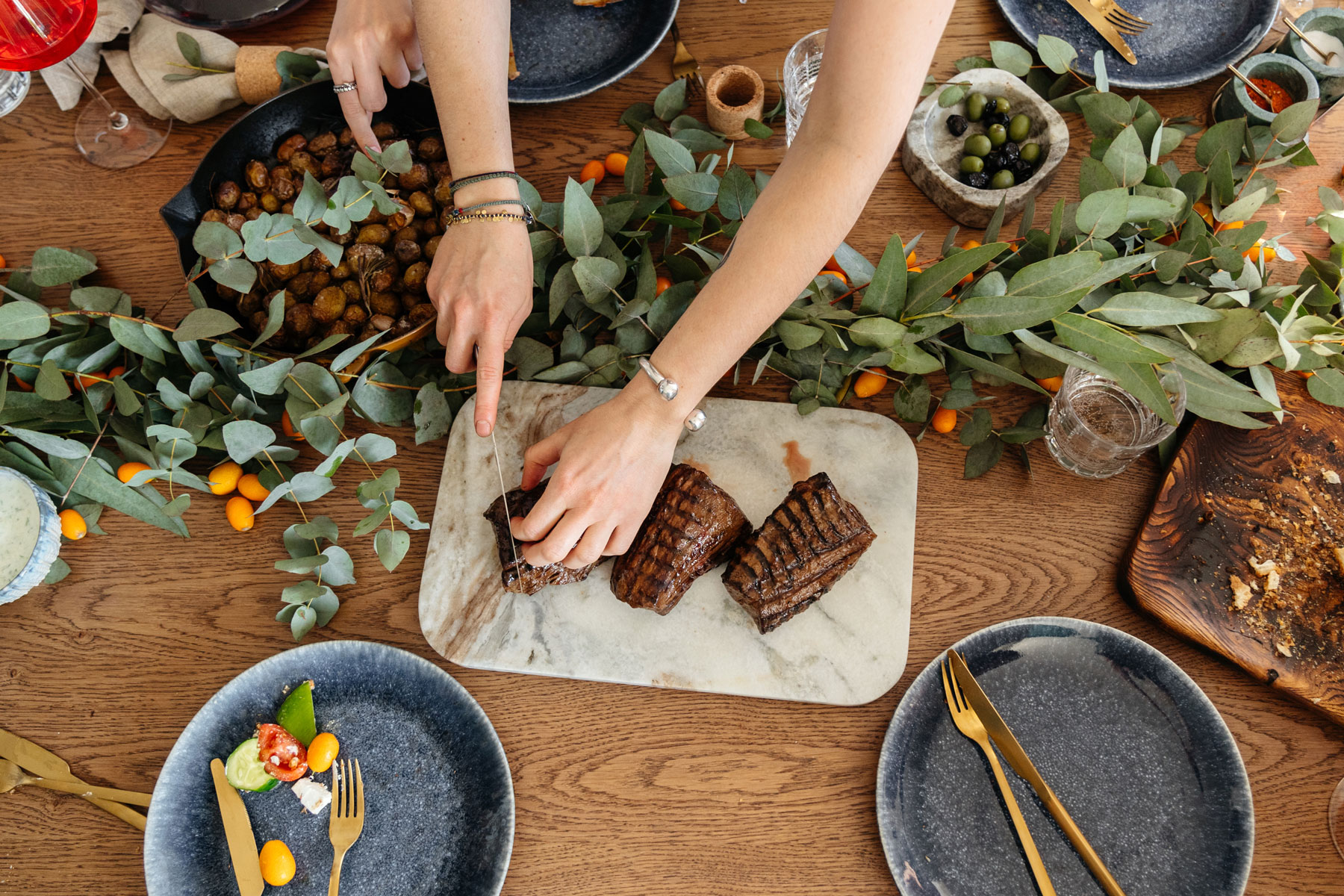 Woman cutting grilled beef on a table setup for the holidays