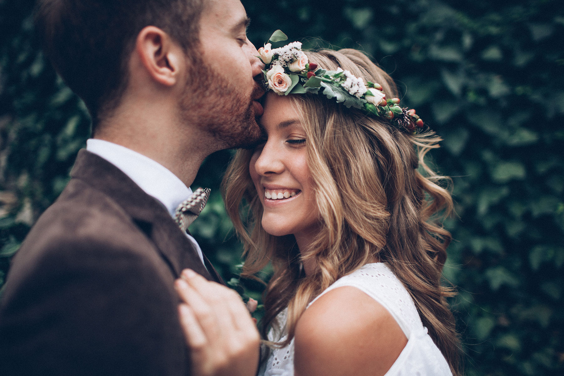 Happy smiling newlyweds in front of greenery