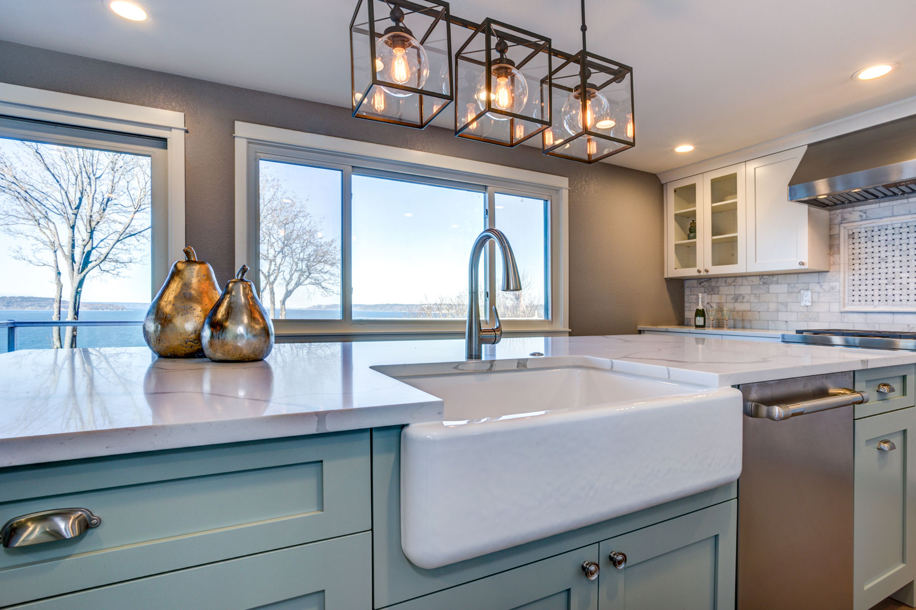 White farmhouse style sink in kitchen with light blue seafoam lower cabinets