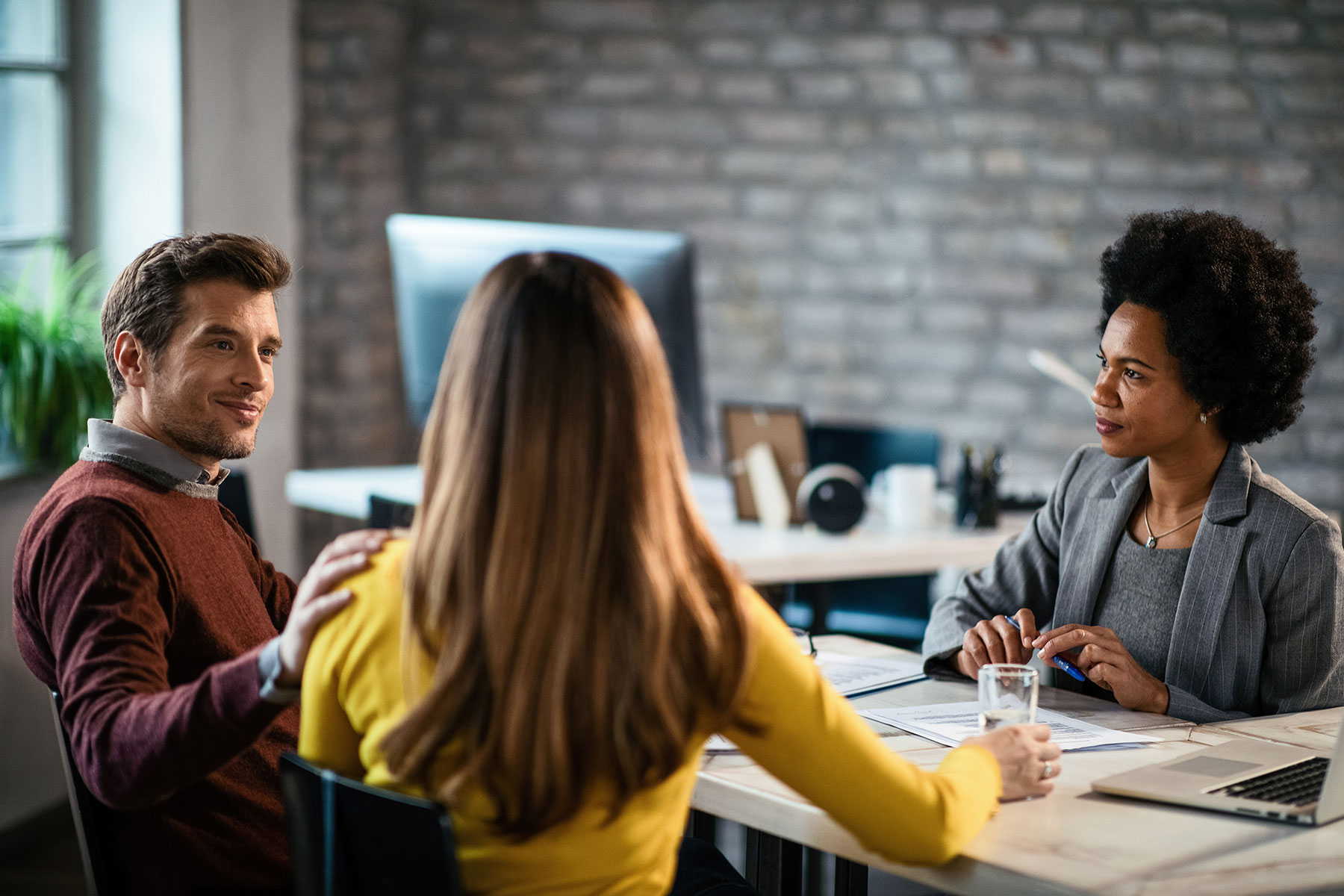 Man and woman sitting at desk across from another woman having a conversation