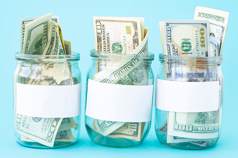 American dollars filling three clear jars with white labels on light blue background
