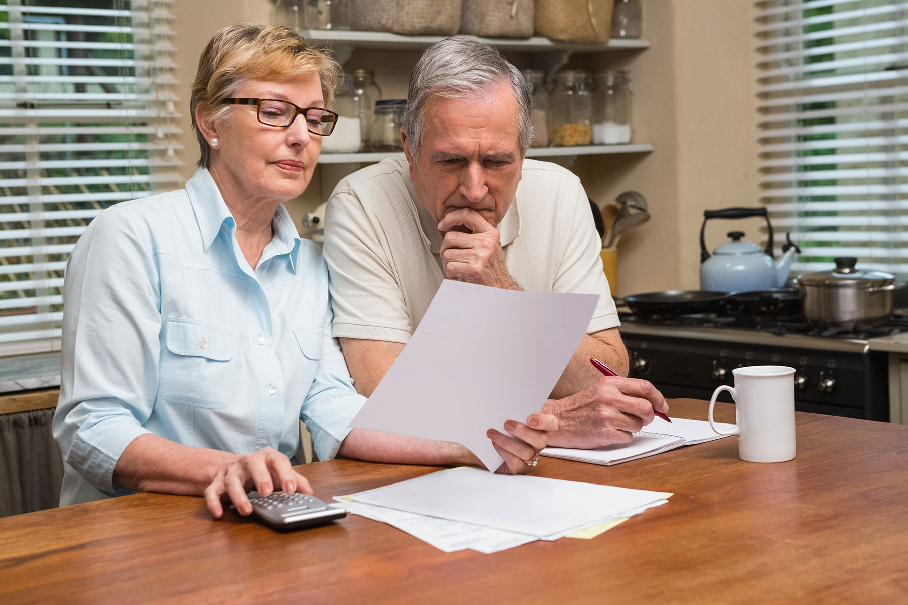Older man and woman studying paperwork at a breakfast nook in their kitchen