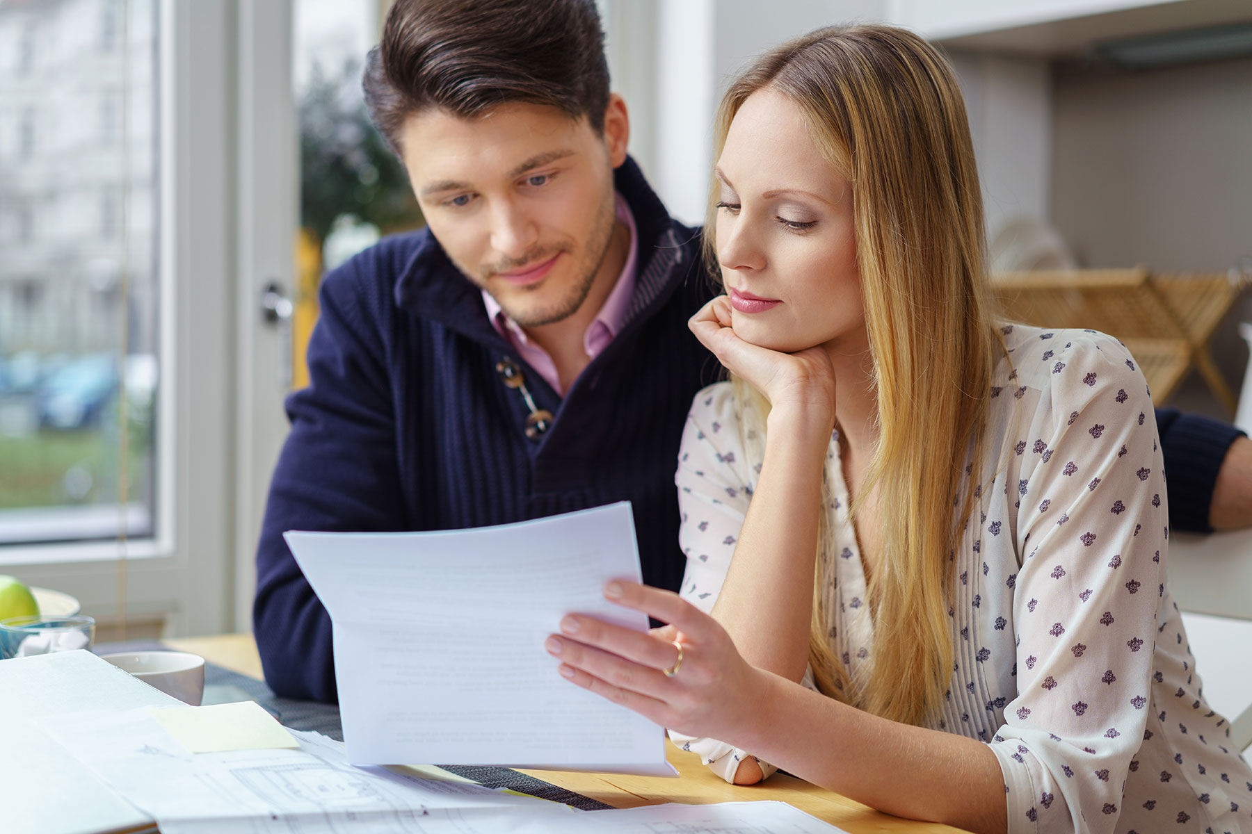 Man and woman sitting at table looking at papers inside of a home