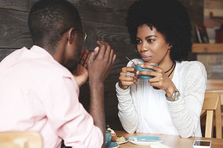 Man and woman in their 20's having a conversation over coffee and cinnamon rolls at a diner