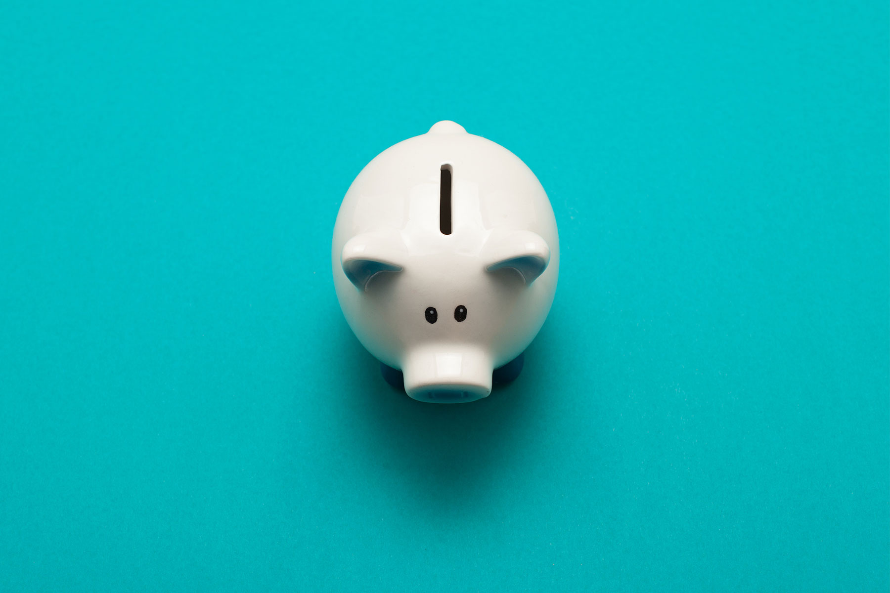 Overhead view of white glass piggy bank on bright blue background