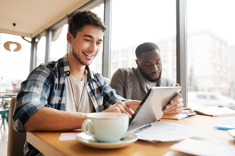 Two young men sitting at a table in a coffee shop working on college course work