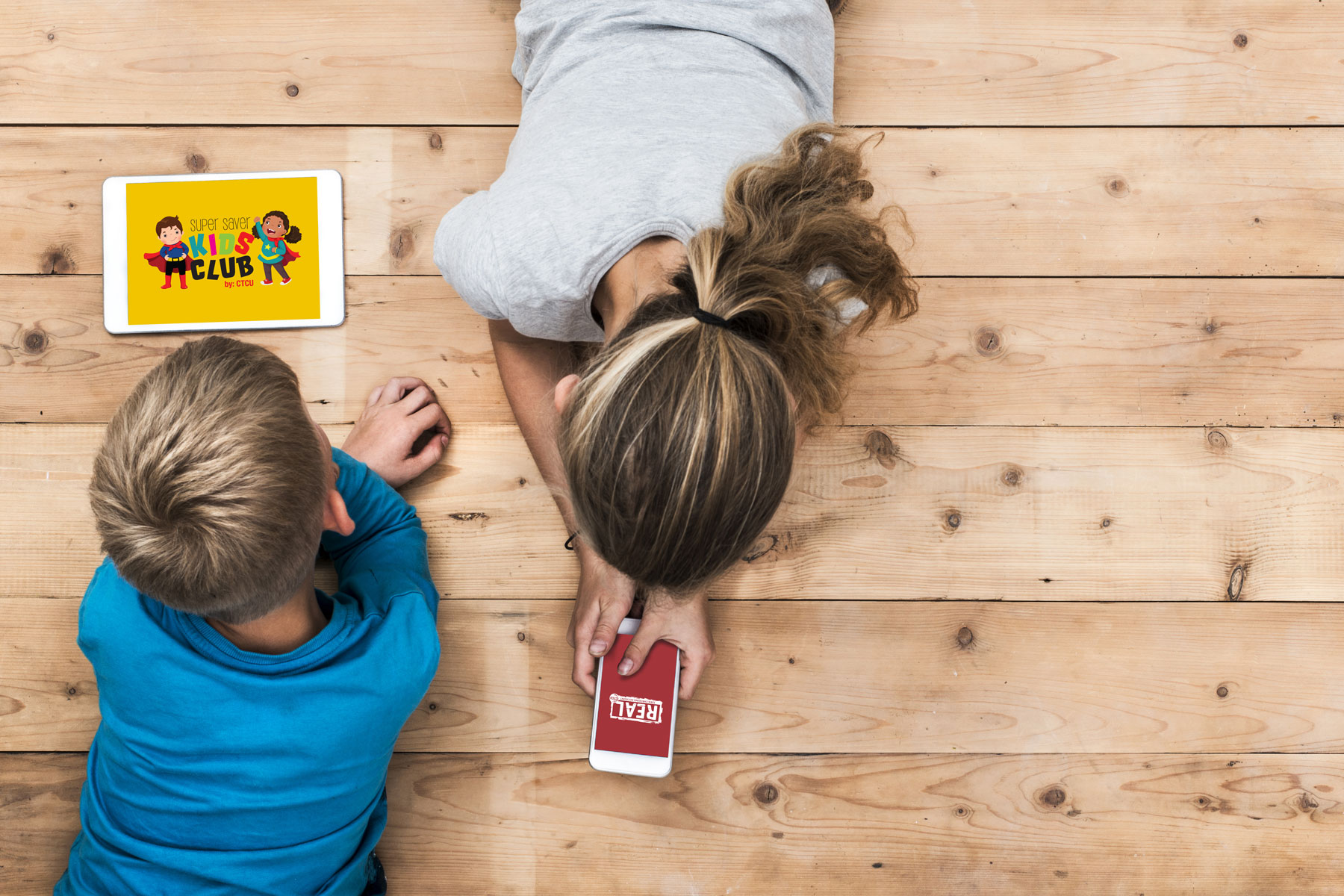 Kids laying on the floor looking at a phone and a tablet device