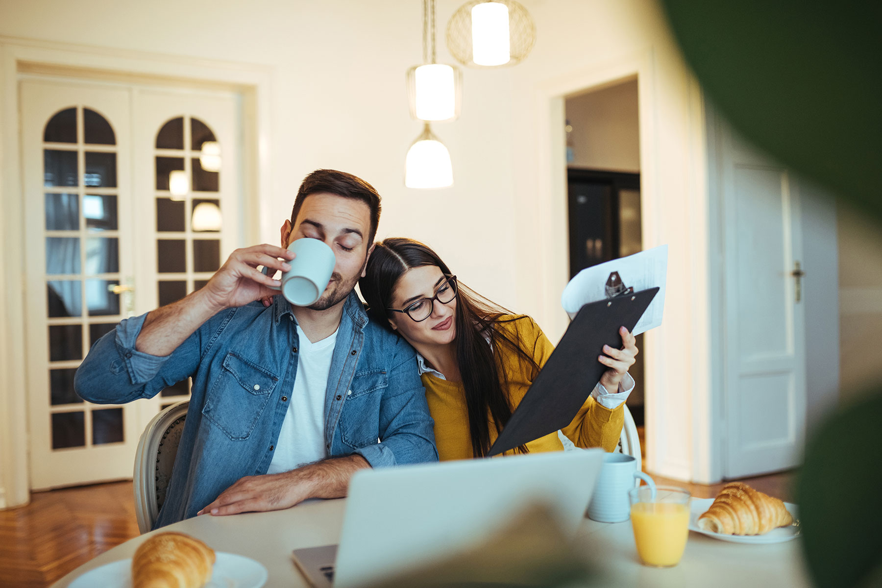 Young couple paying bills and drinking coffee at their dining room table